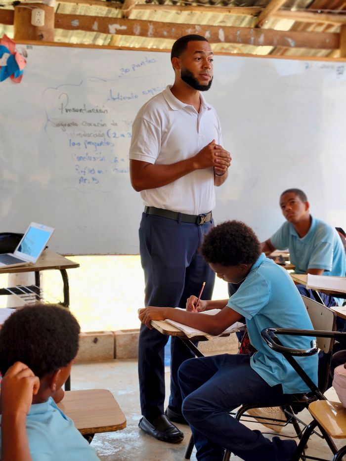 Teacher guiding students in a classroom focused on learning with engaged pupils.